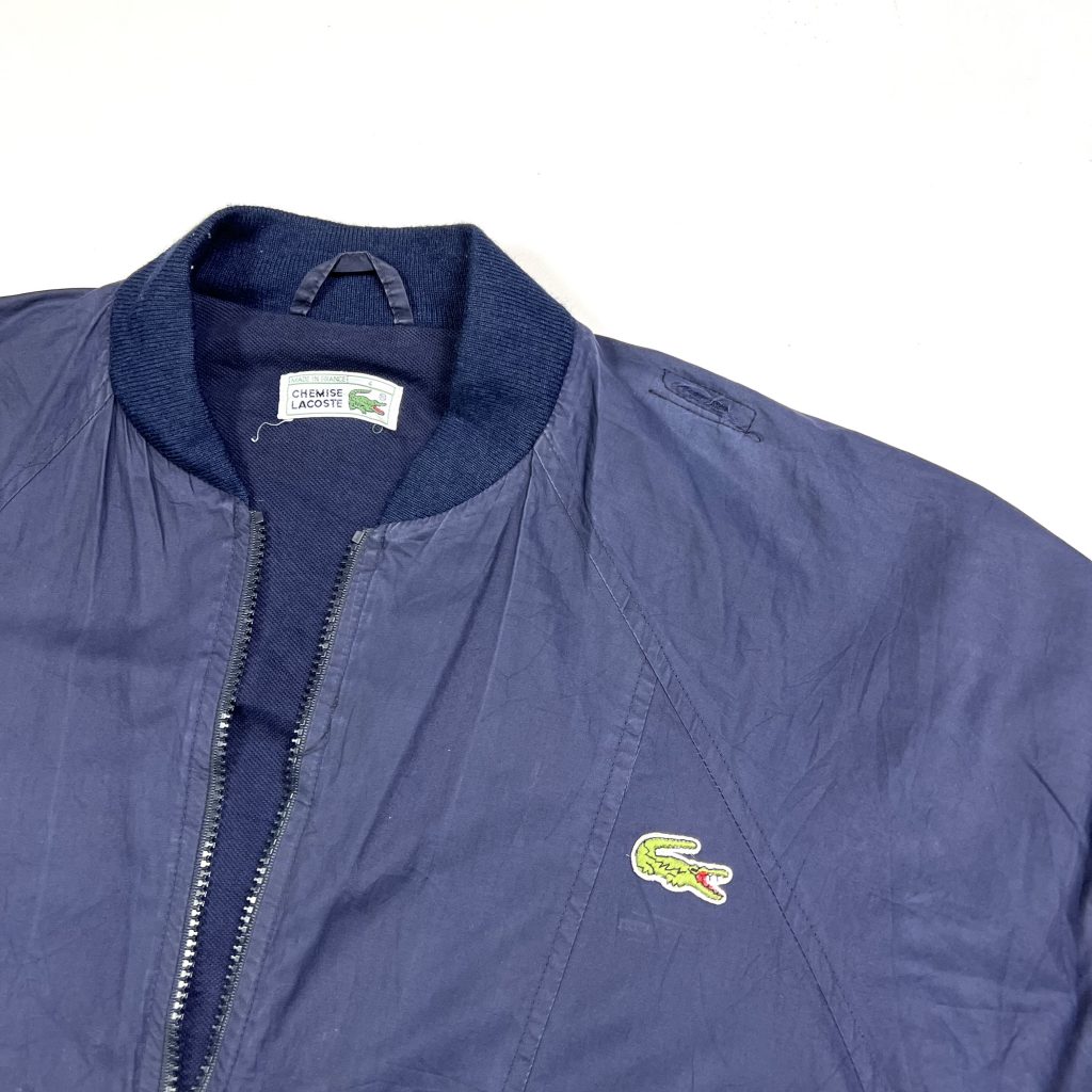 a navy vintage lacoste bomber jacket with embroidered green crocodile logo