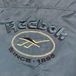 a vintage reebok teal overcoat jacket with embroidered logo on the back