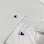embroidered champion “c” logos on a beige sweatshirt
